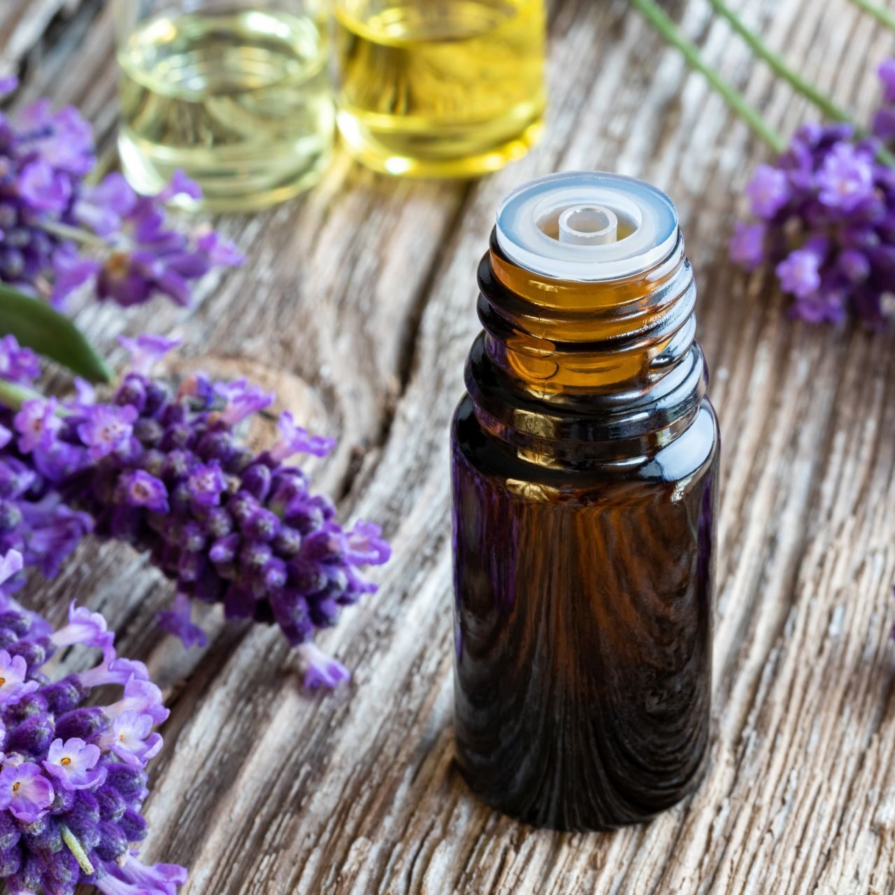 levandule_olej A bottle of essential oil with fresh blooming lavender twigs on a wooden background